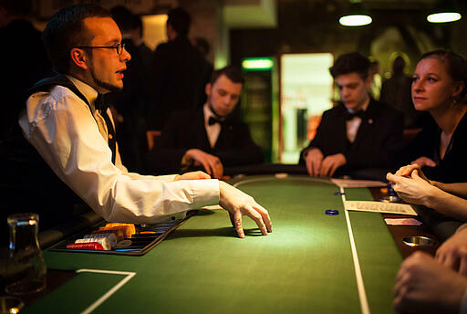 Dealer erklärt Spielregeln beim Pokertisch. Dealer erklärt den Gästen Spielregeln beim Pokern