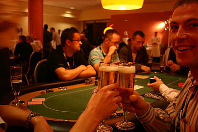zwei Pokerspieler stoßen mit Bier an zwei Pokerspieler stoßen mit einem Bier am Spieltisch an