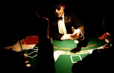 Croupier erklärt Spielregeln beim Blackjack Croupier erklärt im schummrigen Licht Spielregeln beim Blackjack