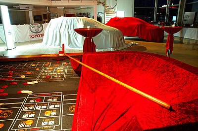 Craps als Idee für eine Kundenveranstaltung Craps-Würfeltisch mit verhüllten Autos im Hintergrund bei einer Produktpräsentation in einem Autohaus.