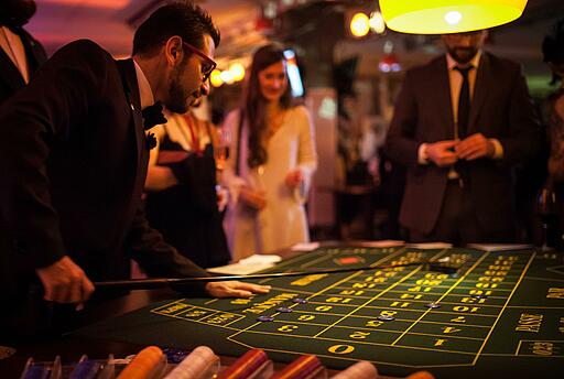 Croupier zahlt Gewinn mit Rateau aus Croupier zahlt Gewinn am Roulette-Tisch mit Rateau aus