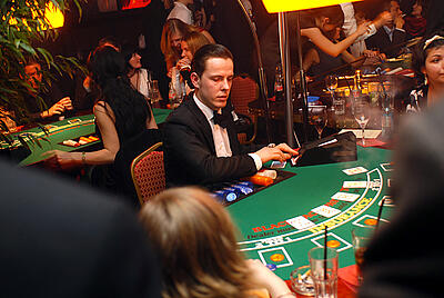 Croupier Tobias teilt Karten beim Blackjack aus Croupier Tobias teilt Karten am vollen Spieltisch beim Blackjack aus