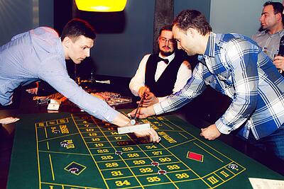 Roulette-Tisch mieten - Sommerfest Idee Gäste eines Sommerfestes machen ihre Einsätze beim Roulette.