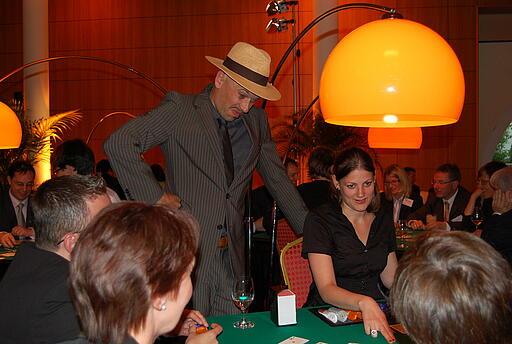 Schauspieler als Walk Act beim Firmenjubiläum der Simcorp GmbH Schauspieler schaut Croupier beim Blackjack über die Schulter und guckt skeptisch.